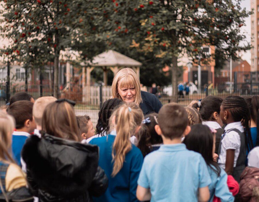 Nancy standing in a playground surrounded by children