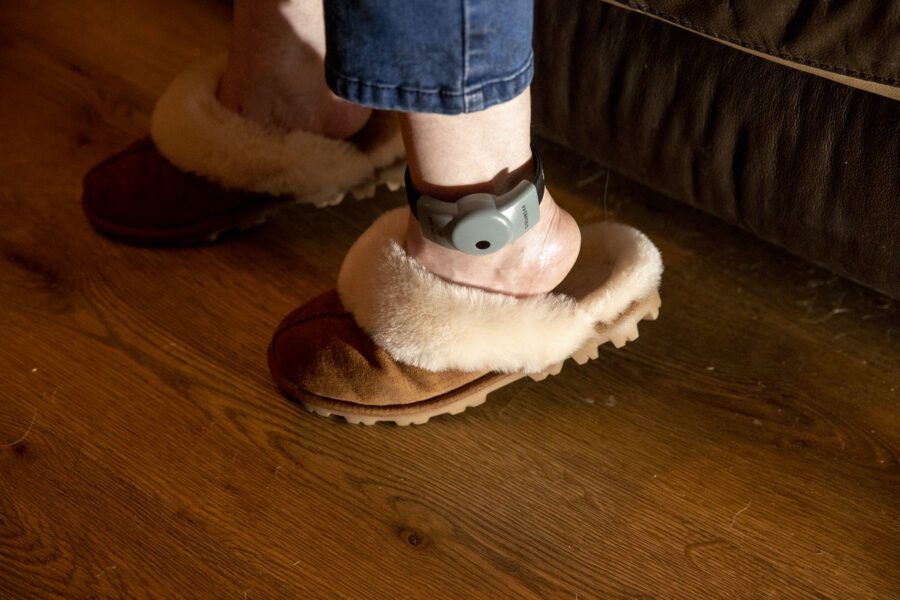 Woman at home with electronic monitoring device on ankle